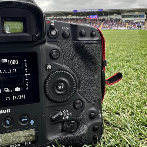 A DSLR camera on grass at the side of a football pitch